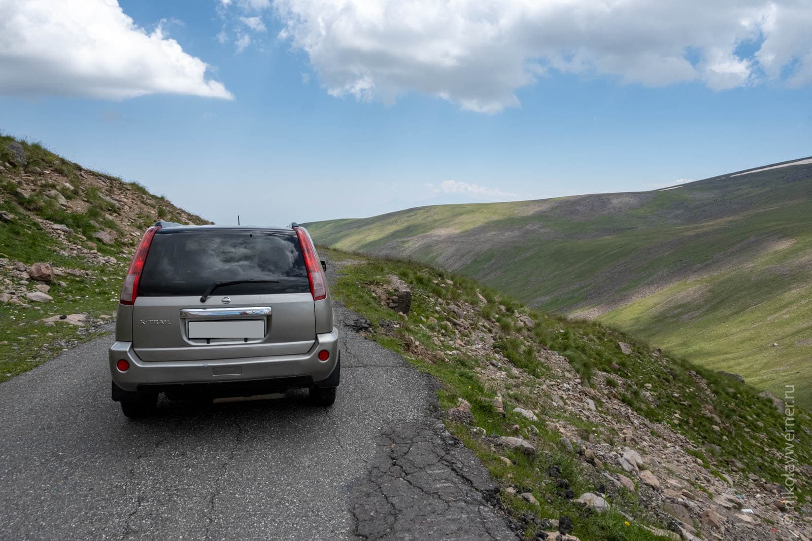 Машина на узкой полосе асфальта. Фотография, иллюстрирующая насколько узкая дорога ведет к Арагацу.